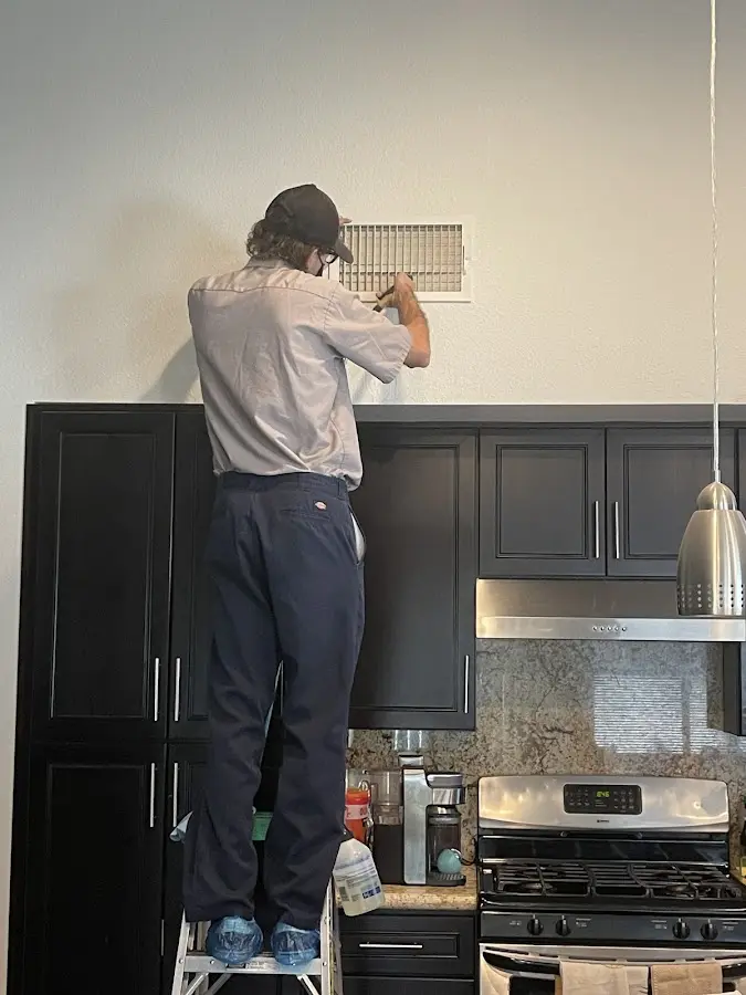 Technician inspecting an air vent during HVAC service in Kalamazoo